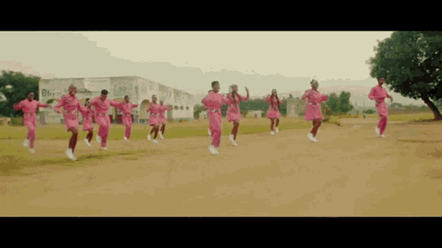 a group of people are dancing on a dirt road in front of a building that says biz