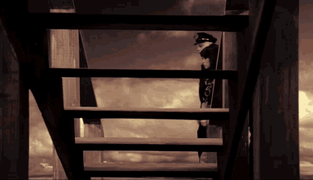 a man in a hat stands on a set of stairs with the letter l on the bottom