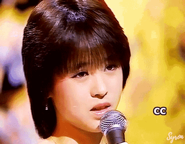 a close up of a woman singing into a microphone with the letters gg visible