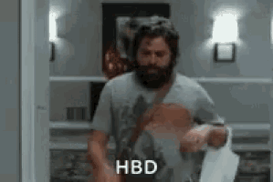a man with a beard is standing in a hallway holding a piece of paper .