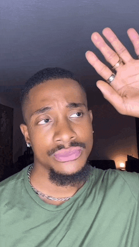 a man with a beard and a ring on his finger is making a face