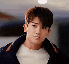 a close up of a young man wearing a white shirt and a blue jacket .