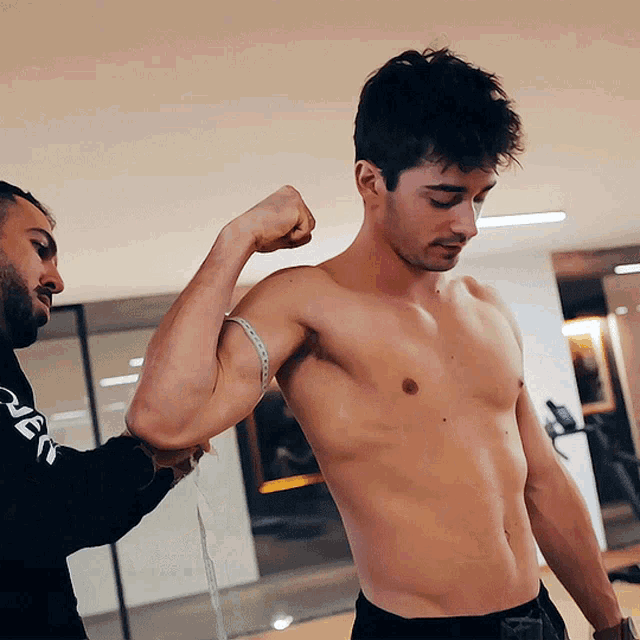 a man measuring another man 's arm with a tape measure