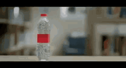 a bottle of water is sitting on a wooden table .
