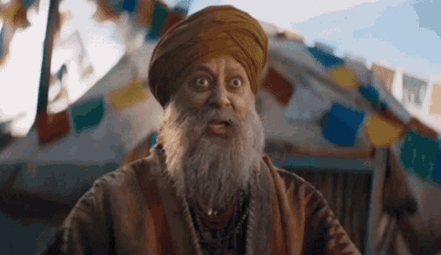 a man with a beard and a turban is making a funny face .