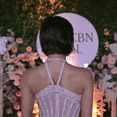the back of a woman standing in front of a sign that says cbn