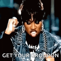 a woman in a leather jacket is holding her fist up in the air and says `` get your groupon '' .