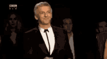 a man in a suit and tie is clapping his hands