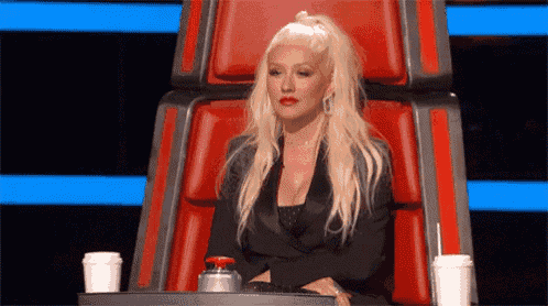 a blonde woman is sitting in a red chair with two cups of coffee .