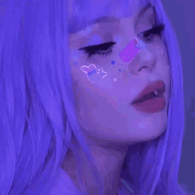 a woman with purple hair has stickers on her face .