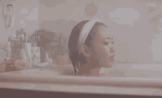 a woman is taking a bath in a bathtub with a towel around her head .