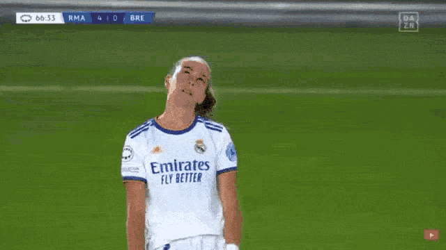 a soccer player wearing an emirates fly better shirt looks up at the sky .