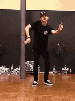 a man in a black shirt and hat is dancing in a room .