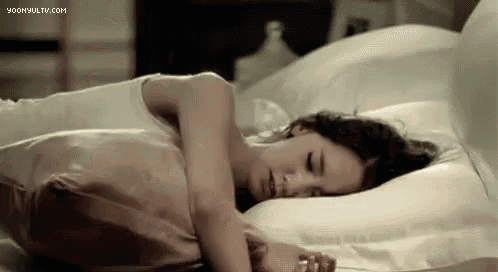 a woman is sleeping on a bed with a pink pillow and the website yoonsultv.com is visible in the corner .