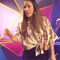 a woman in a floral shirt is standing in front of a star on a stage .