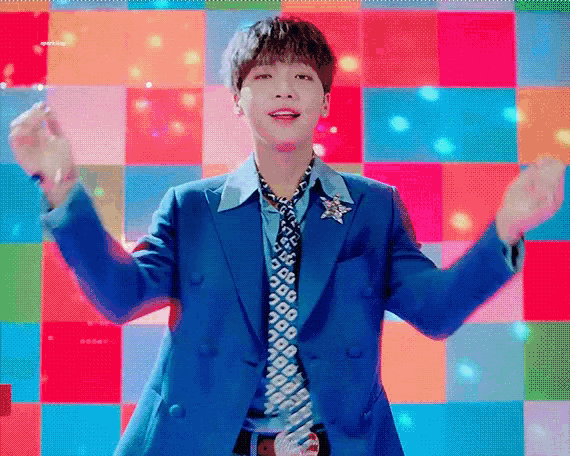 a young man in a blue suit and tie is dancing in front of a colorful background .