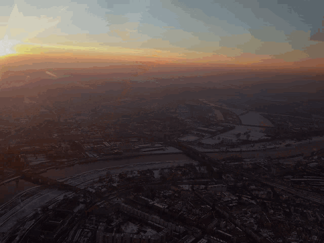 an aerial view of a city at sunset with the sun shining brightly