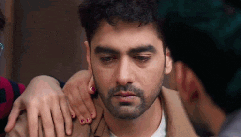 a man with a beard is being comforted by a woman who is holding his shoulder .