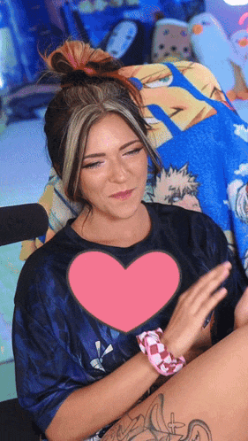 a woman wearing a blue shirt with a pink heart in the middle