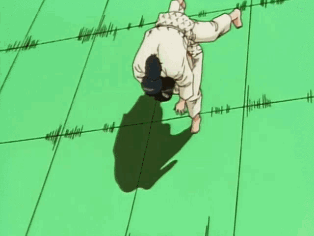 a man in a white shirt is doing a handstand on a green mat