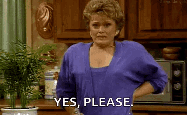 a woman in a purple shirt is standing in a kitchen with her hands on her hips and says yes , please .