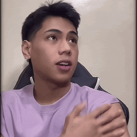 a young man in a purple shirt is sitting in a chair and looking at the camera .