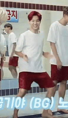 a man in a white shirt and red shorts is dancing in front of a sign that says " bg "