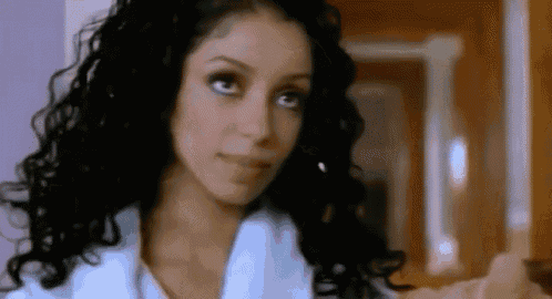 a close up of a woman 's face with curly hair and a white coat .