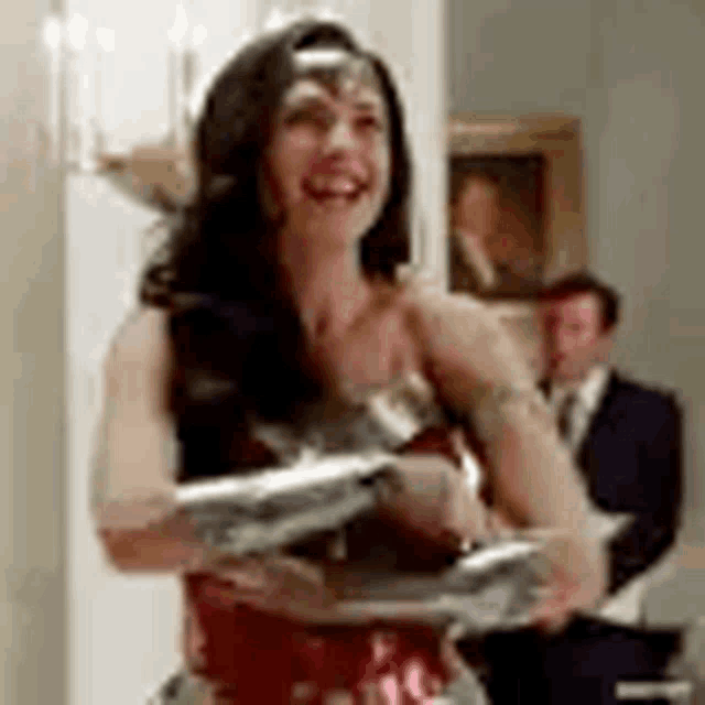 a woman in a wonder woman costume is smiling and holding a sword in a room .