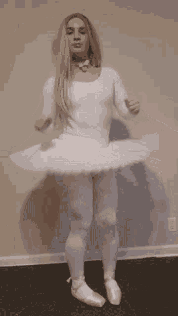 a woman in a white tutu and pointe shoes is dancing in a room .
