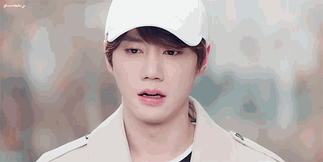 a young man wearing a white baseball cap and a tan coat