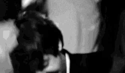 a black and white photo of a man and a woman kissing each other .