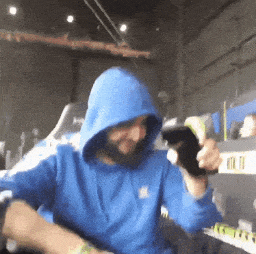 a man wearing a blue hoodie holds a cell phone