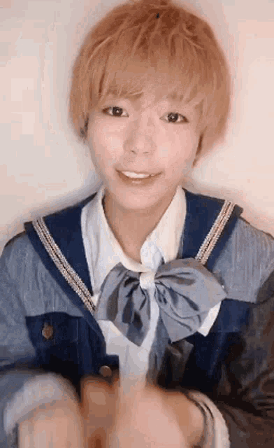 a girl with short blonde hair is wearing a blue jacket and a white shirt with a bow tie .