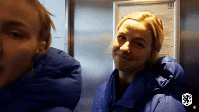 a woman in a blue jacket stands next to another woman