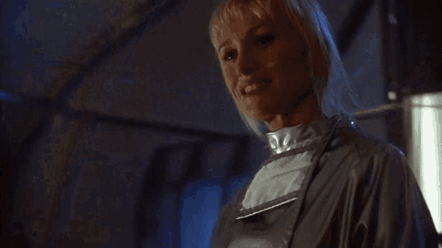 a woman with blonde hair is smiling and wearing a gray jacket