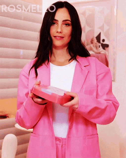 a woman in a pink suit is holding a pink box with the word rosmelo on the bottom