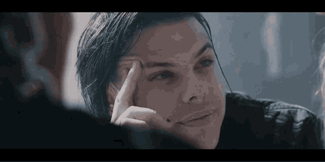 a man is looking at himself in a mirror while holding his hand to his forehead .