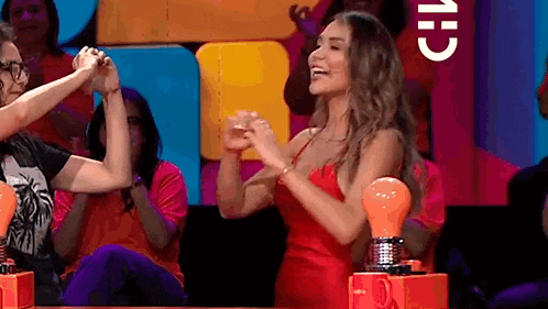 a woman in a red dress is holding a man 's hand while sitting in front of a light bulb .