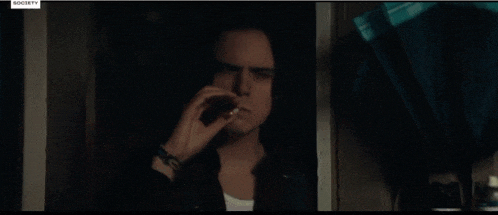 a man smoking a cigarette in a dark room with a society tv logo