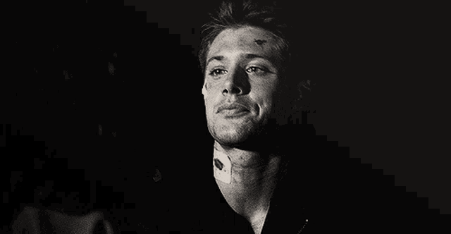 a black and white photo of a man with a tattoo on his forehead .