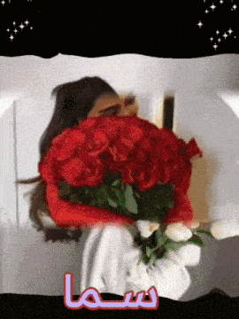 a woman holding a large bouquet of red roses and white roses with arabic writing