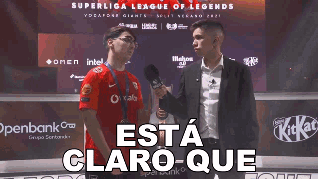 a man holding a microphone stands in front of a superliga league of legends sign