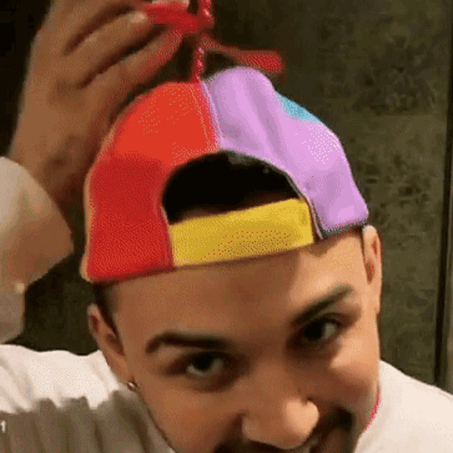 a man wearing a hat with a red yellow and purple stripe on it