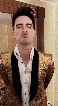 a man in a gold tuxedo and white shirt is blowing a kiss .