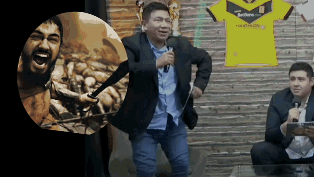 a man in a suit is holding a microphone in front of a yellow shirt that says ' marathon ' on it