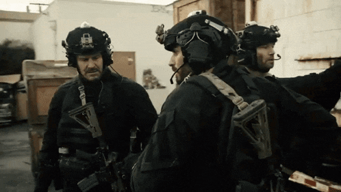 a group of soldiers are standing next to each other and one of them is wearing a helmet with a padlock on it