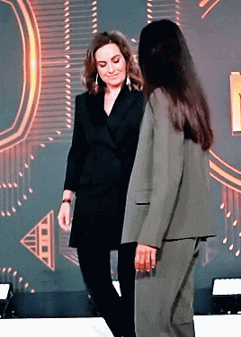 two women are standing next to each other and one is wearing a green suit