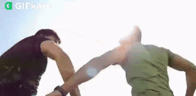 a couple of men are standing next to each other and fighting each other .