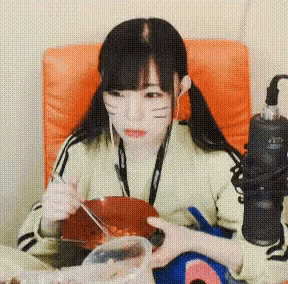a girl is sitting in a chair eating food with chopsticks .